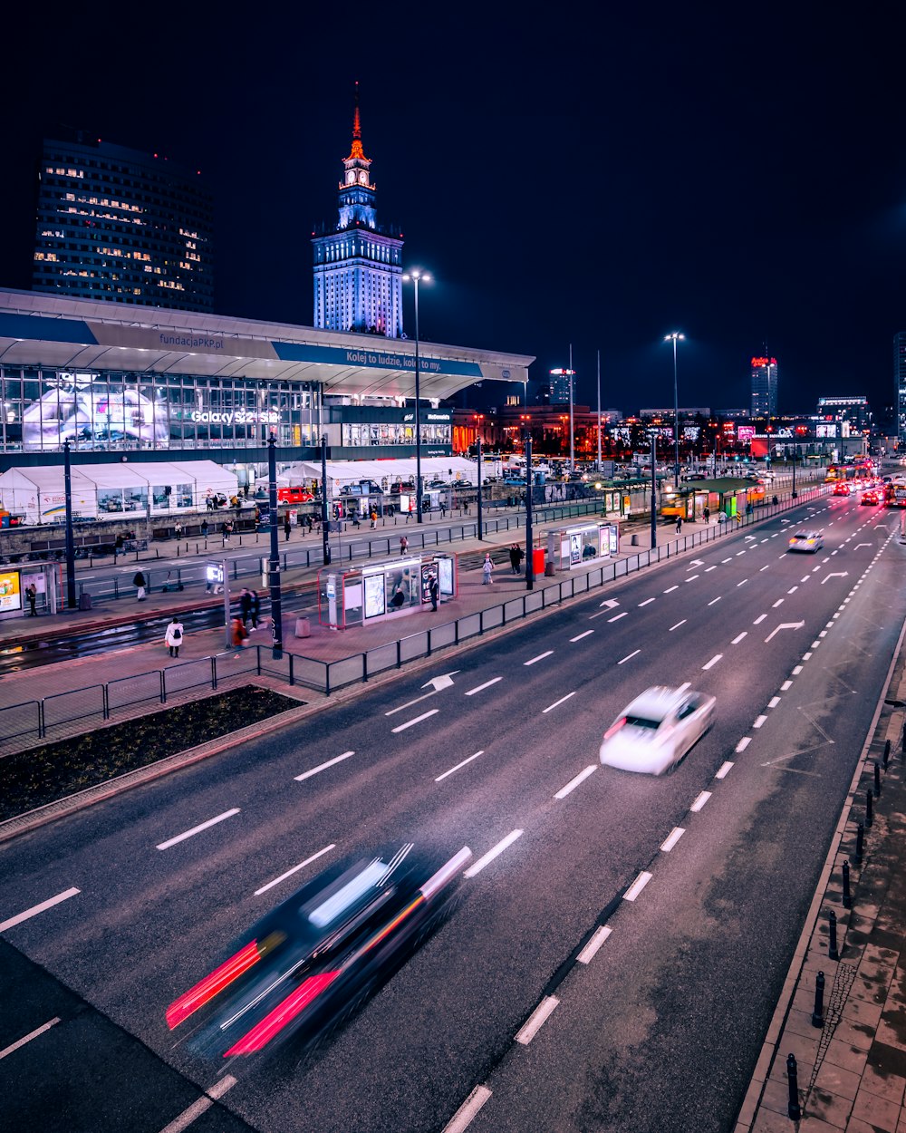 a city street at night with cars driving on it