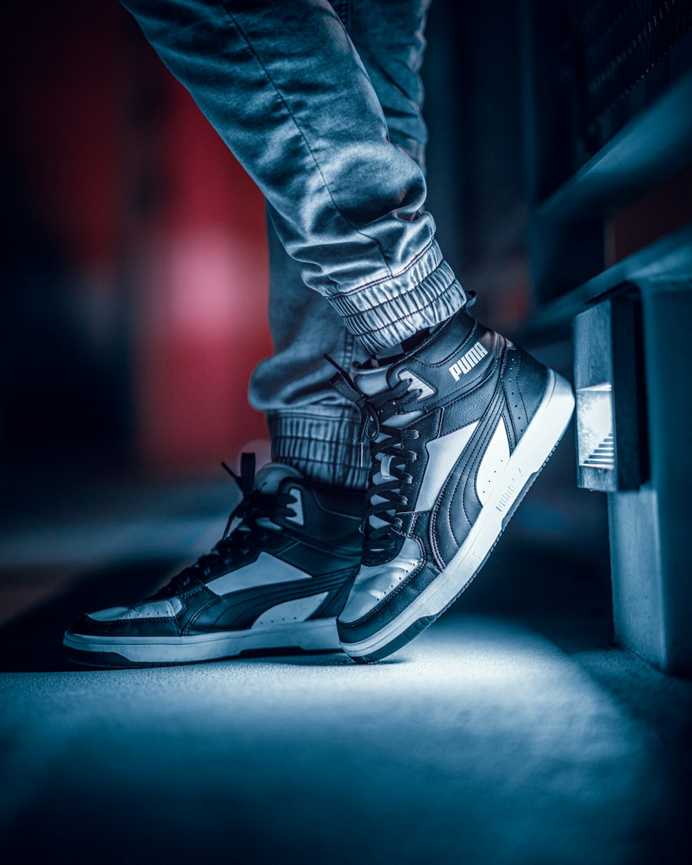 a person wearing black and white sneakers standing on a ledge