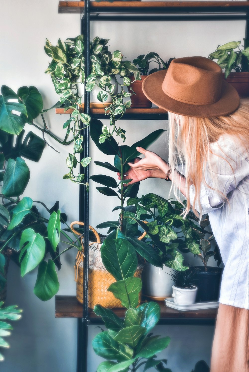 a woman in a hat is looking at plants