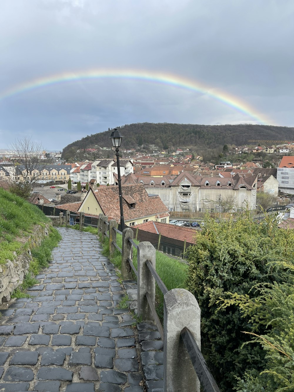 a cobblestone path with a rainbow in the background