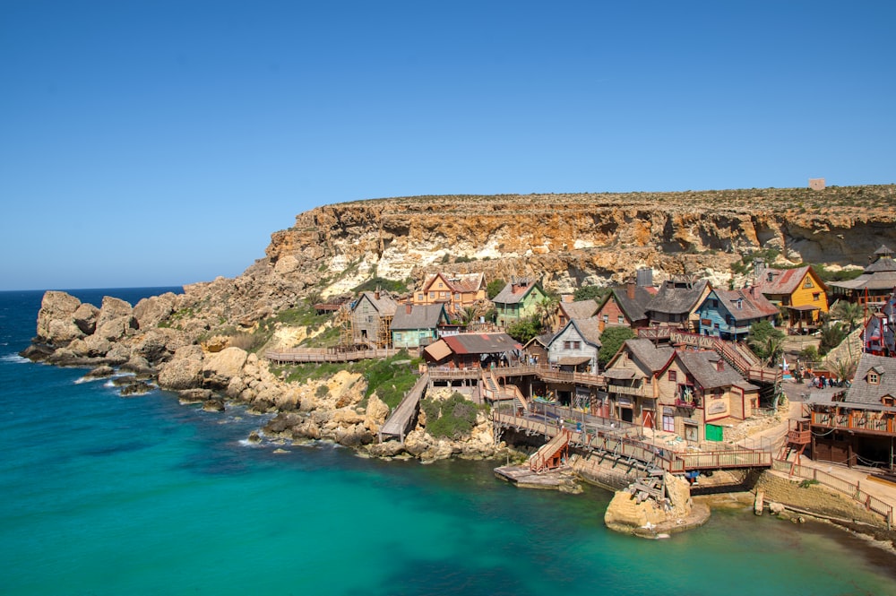 a group of houses sitting on top of a cliff next to the ocean