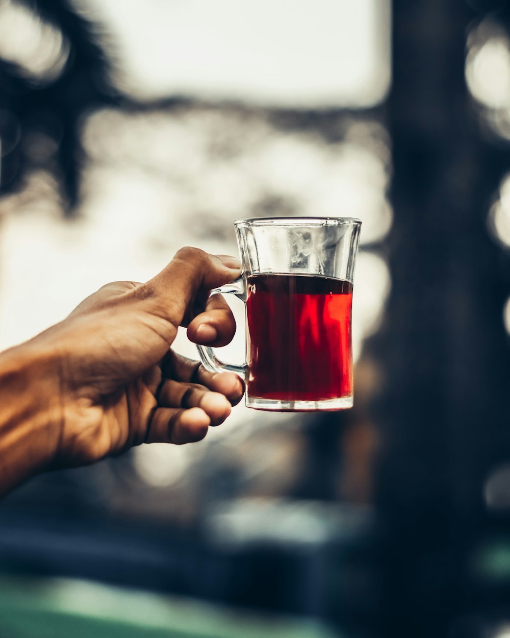 a person holding a glass of tea in their hand