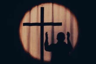 a silhouette of a person holding a cross