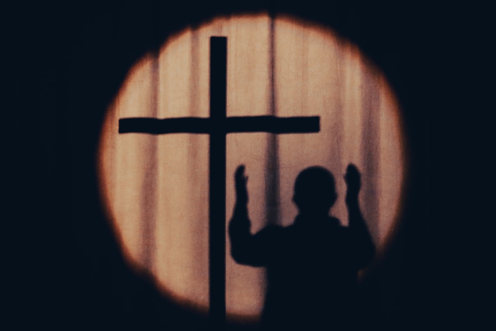 a silhouette of a person holding a cross