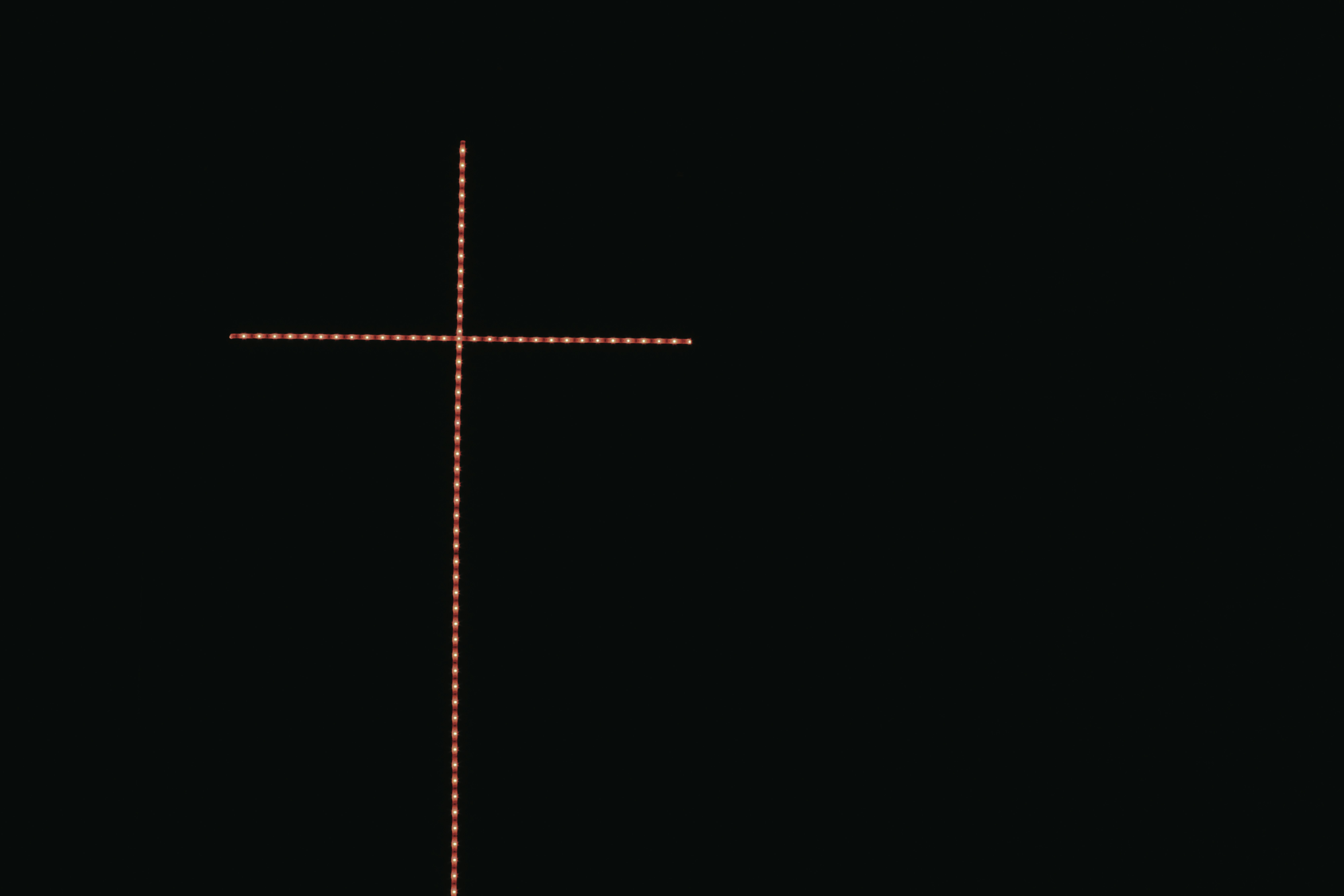 une croix sur fond noir avec une lumière rouge