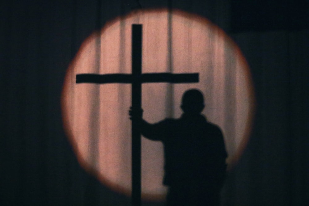 a man holding a cross in front of a window