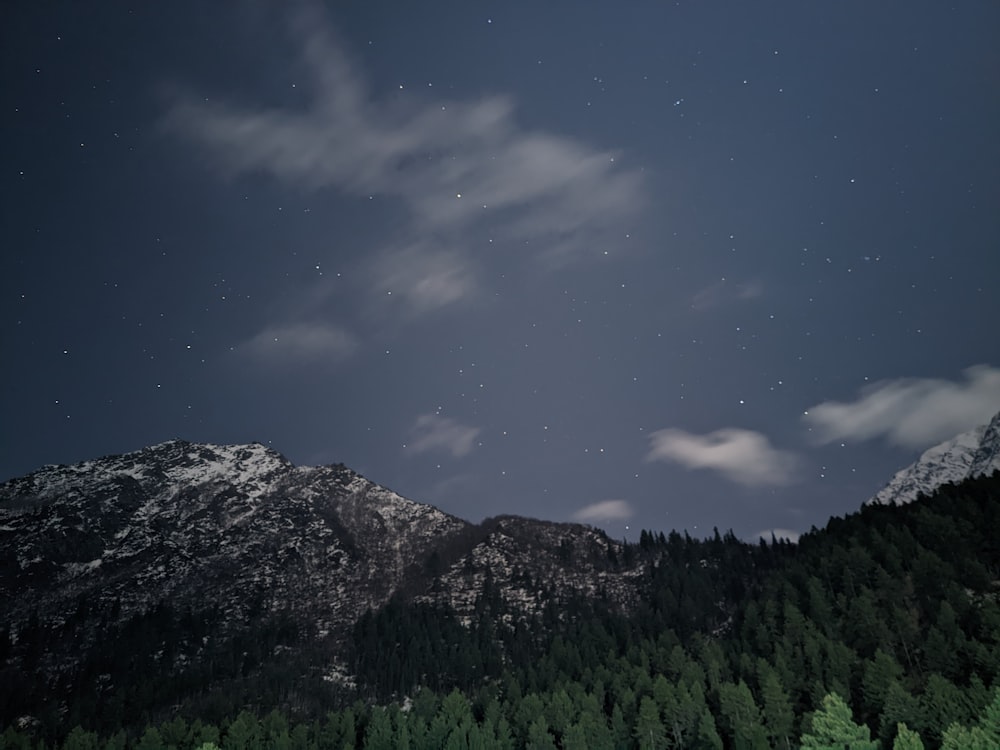 the night sky with stars above a mountain range