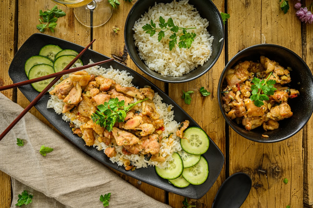 a plate of chicken and rice with cucumbers and a glass of wine