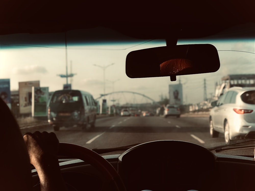 a man driving a car down a street next to a white car