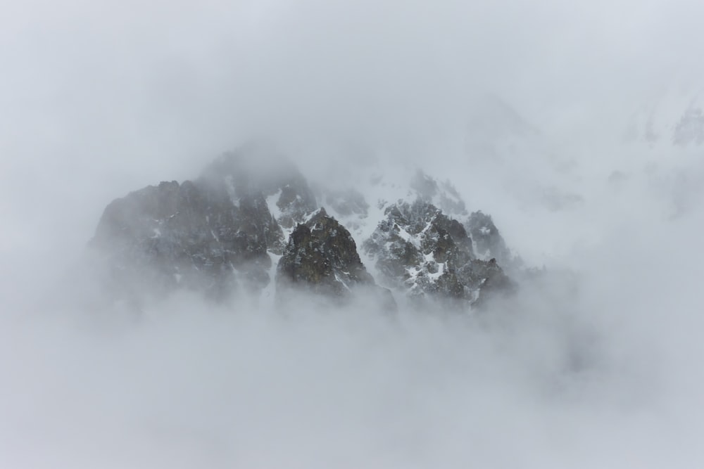 a mountain covered in snow and clouds in the fog