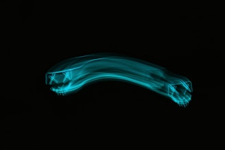 A blue neon light trail forms the shape of a stylized car set against a dark background. The design features elongated, flowing lines and suggests motion and speed.