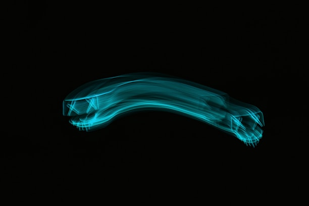A blue neon light trail forms the shape of a stylized car set against a dark background. The design features elongated, flowing lines and suggests motion and speed.