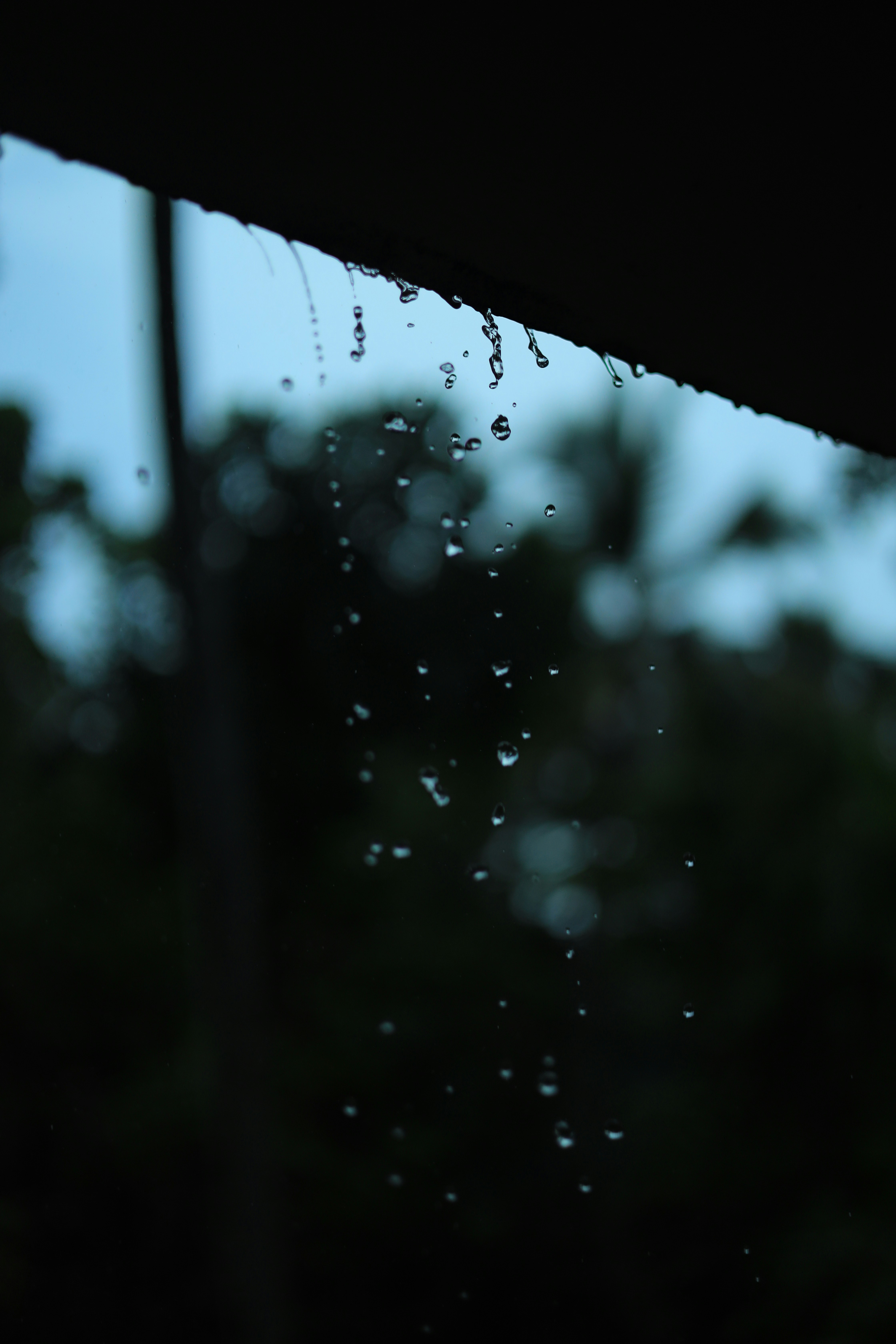 a window covered in rain with trees in the background