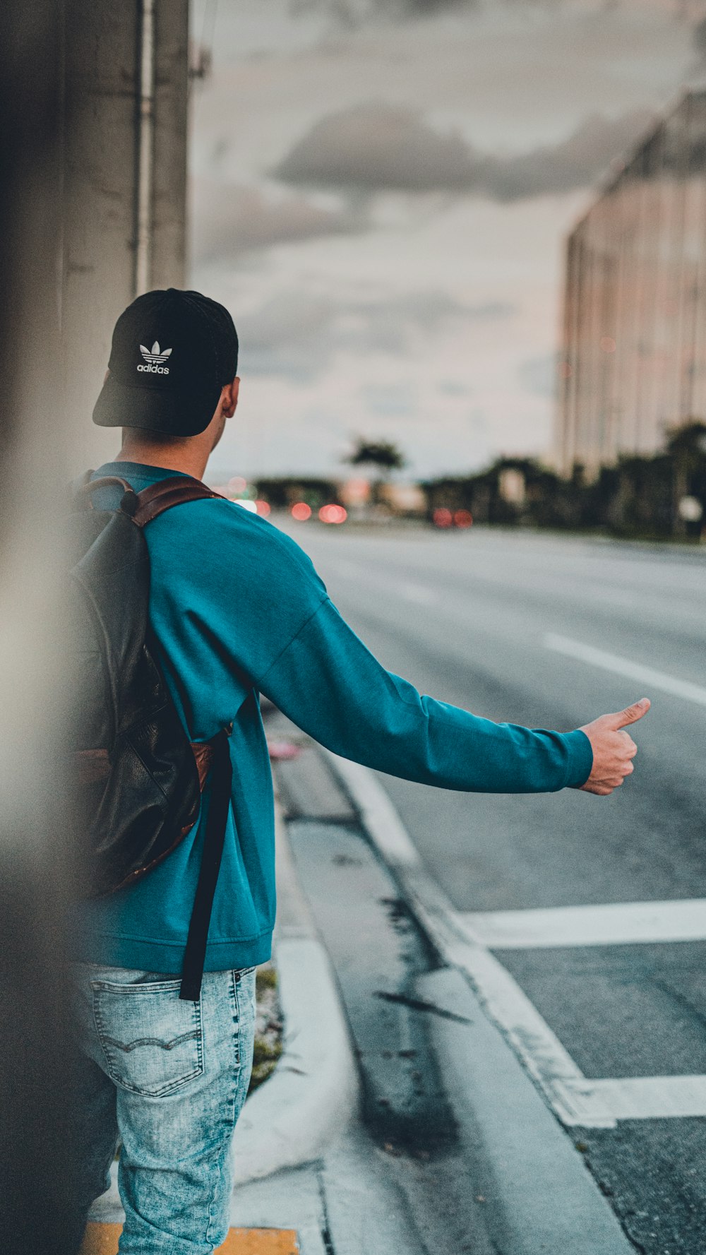 a man with a back pack is pointing at the street