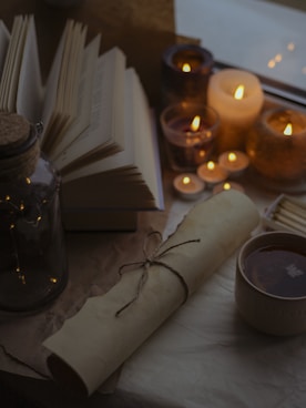 a table topped with books and candles next to a cup of coffee