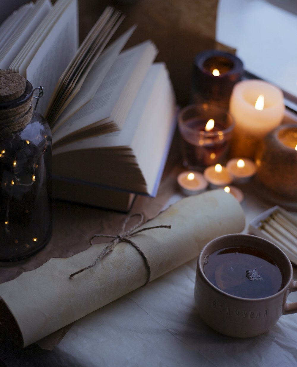 a table topped with books and candles next to a cup of coffee