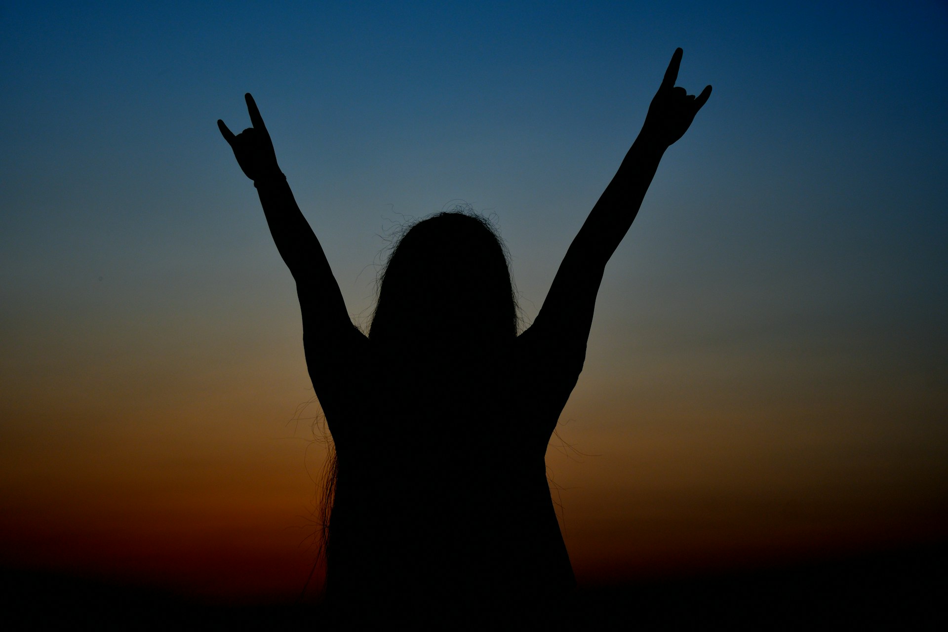 a silhouette of a woman raising her arms in the air