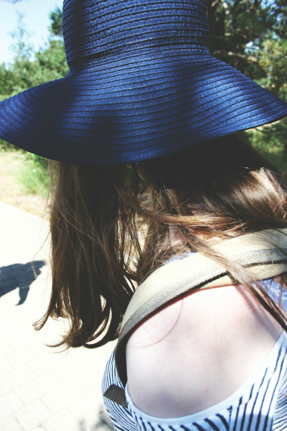 a woman wearing a blue hat walking down a sidewalk