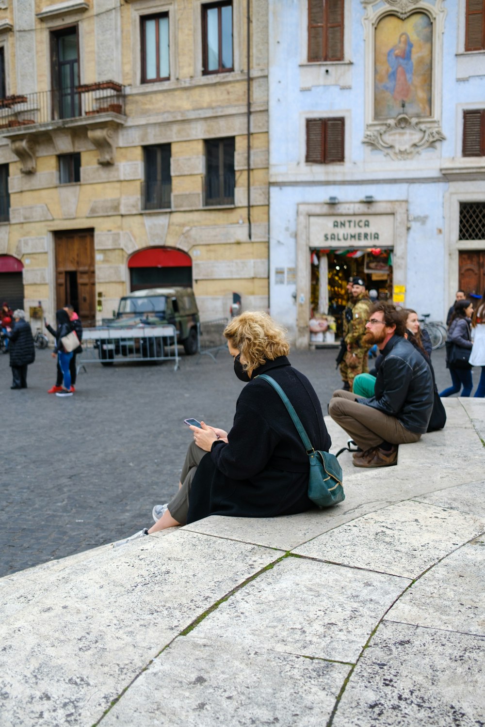 a woman sitting on a ledge looking at her cell phone