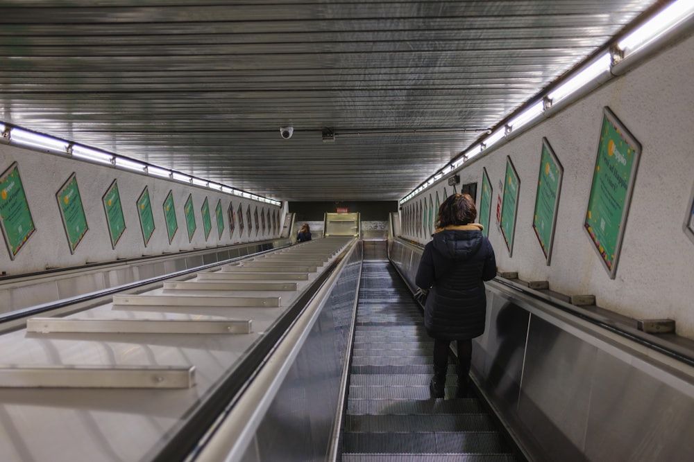 a woman walking down an escalator in a subway