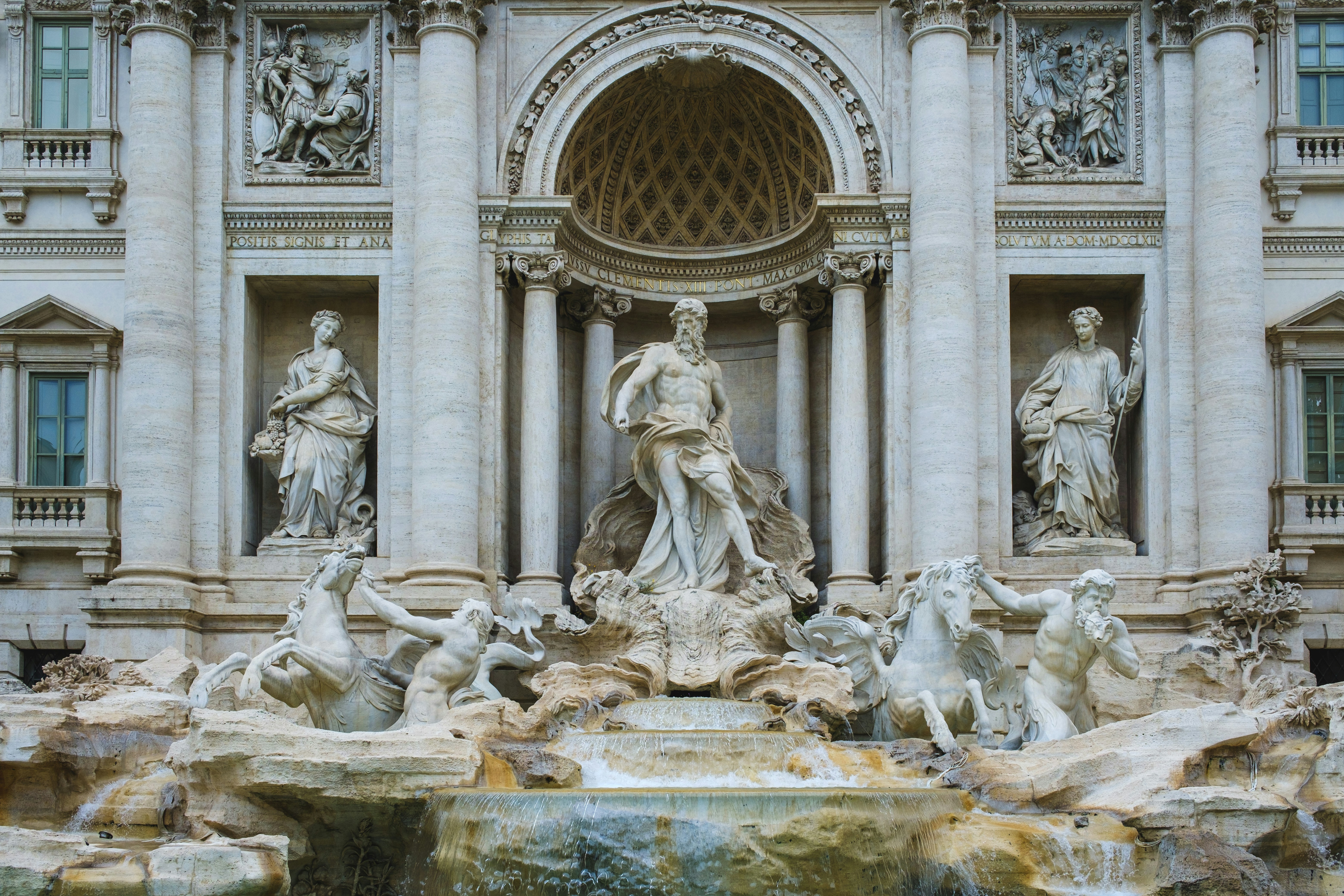 a fountain in front of a building with statues on it