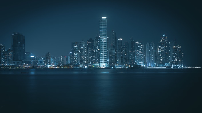 a city skyline at night with a body of water in the foreground