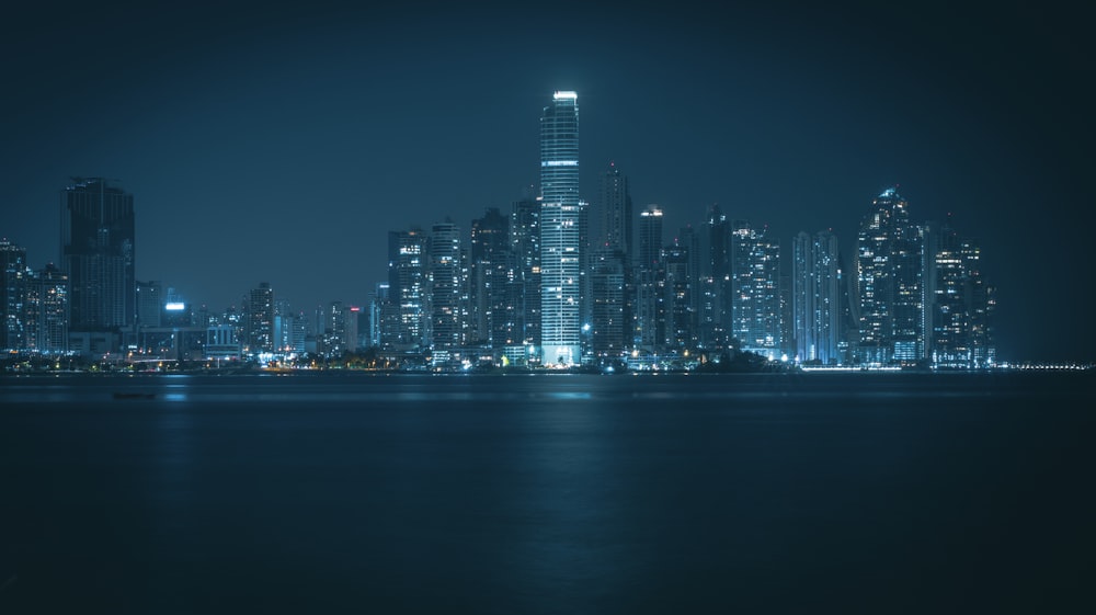 a city skyline at night with a body of water in the foreground