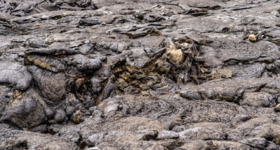 Dark, uneven lava rock features a rough, textured surface with some areas smoother and others more jagged. The landscape appears barren and devoid of vegetation, emphasizing the natural formations created by molten rock cooling and solidifying.