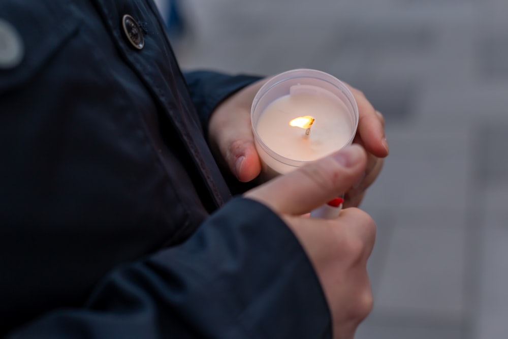 a person holding a lit candle in their hands