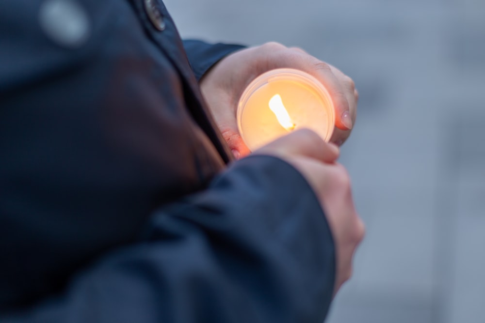 a person holding a lit candle in their hands