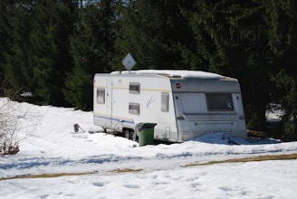 a trailer parked in the snow next to a forest