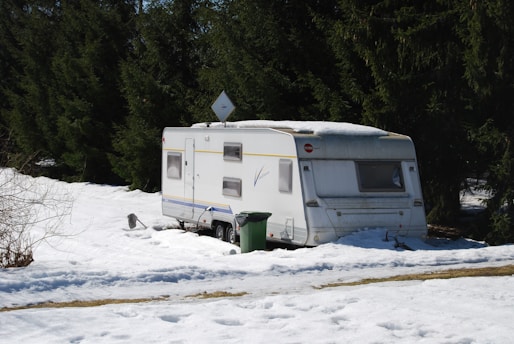 a trailer parked in the snow next to a forest