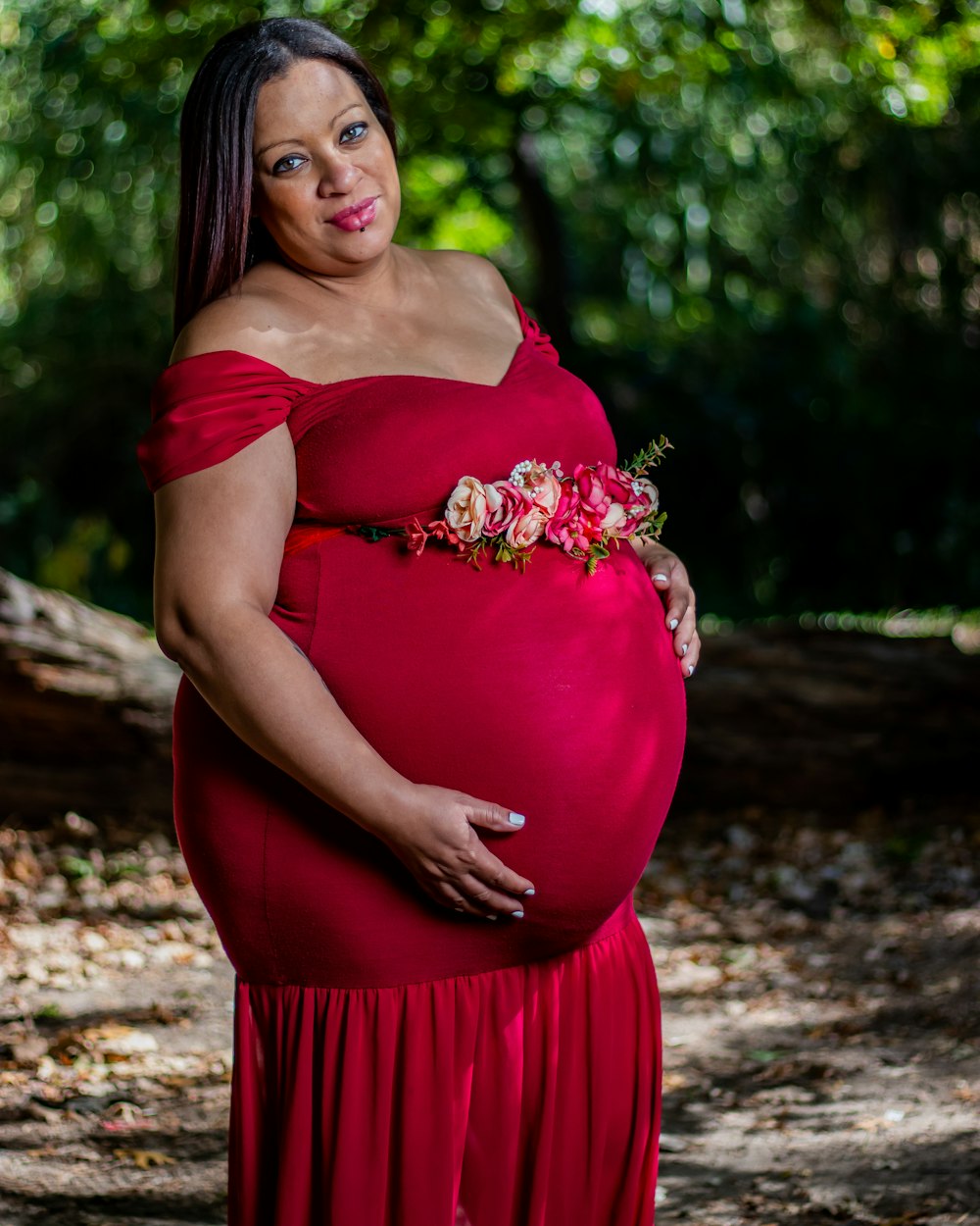 a pregnant woman in a red dress poses for a picture