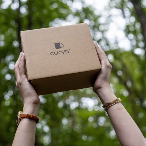 a person holding a box in front of a tree