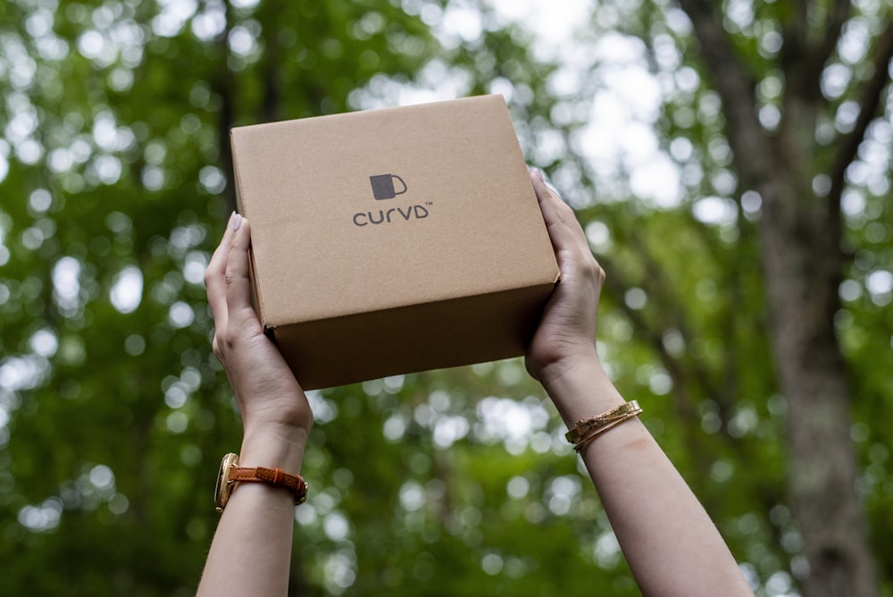 a person holding a box in front of a tree