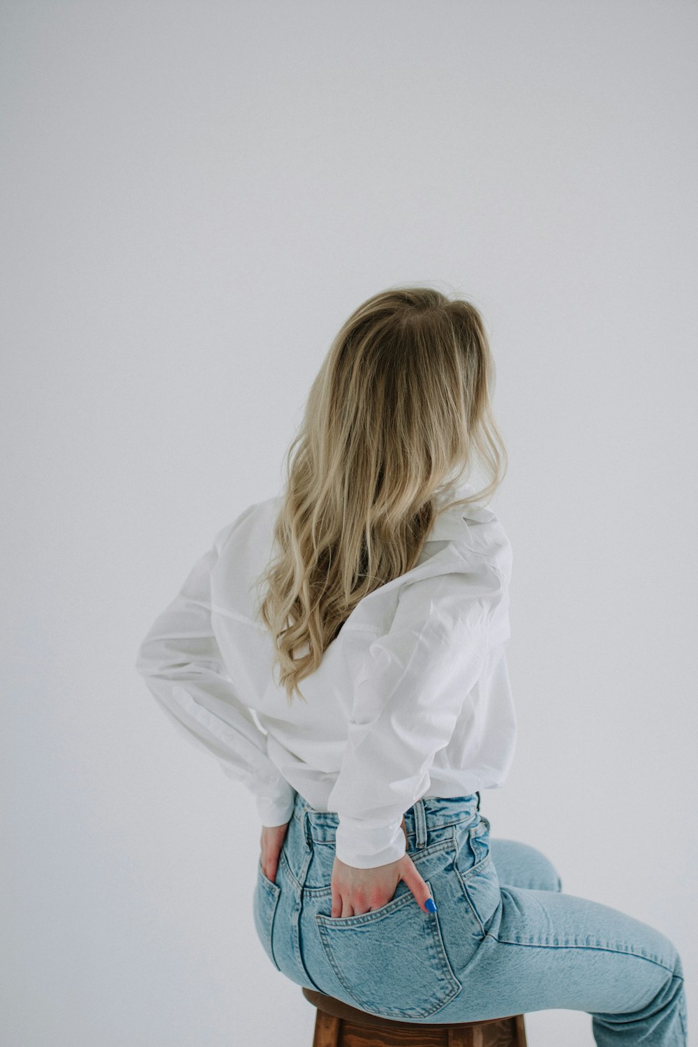 a woman sitting on top of a wooden stool