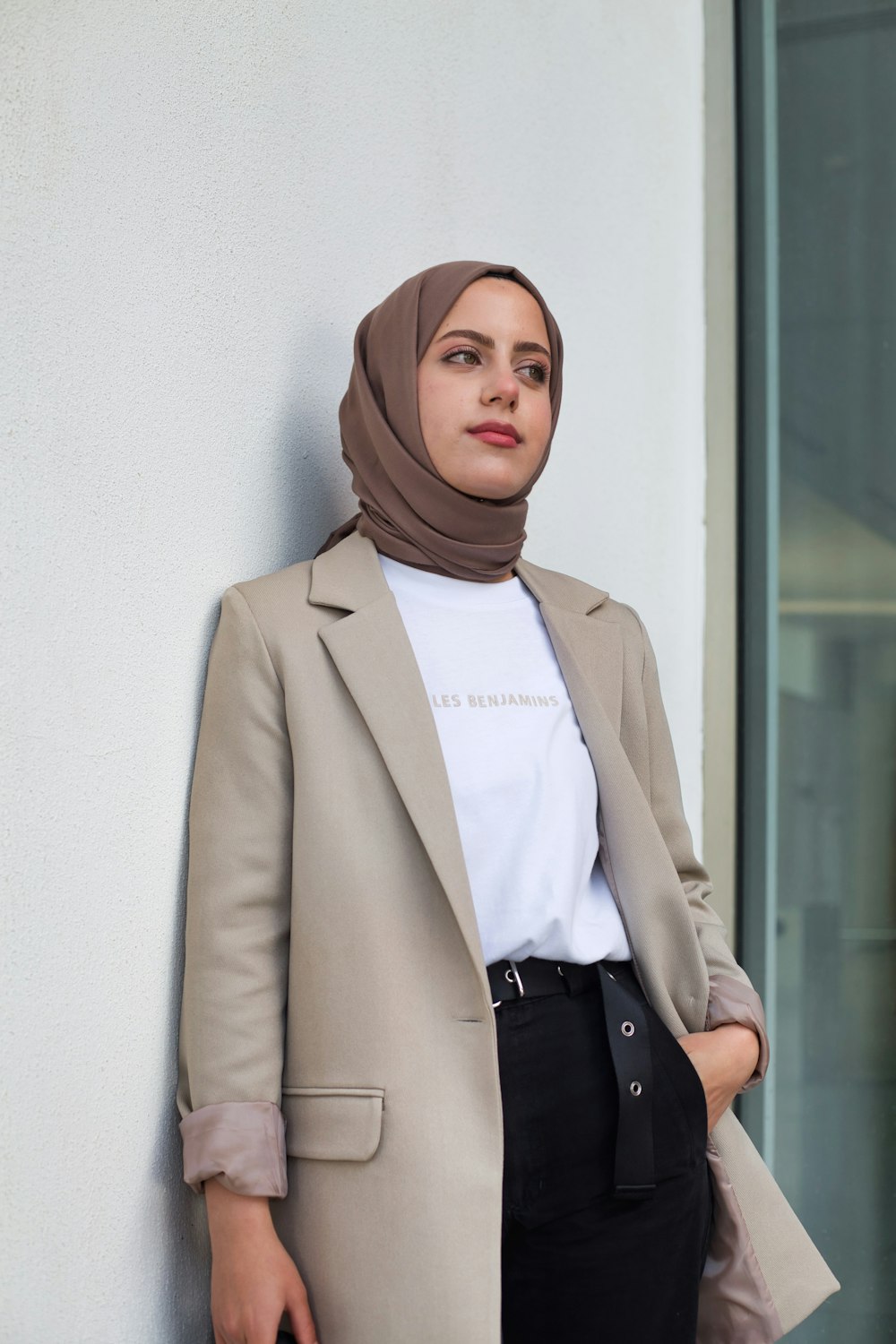 a woman in a hijab leaning against a wall