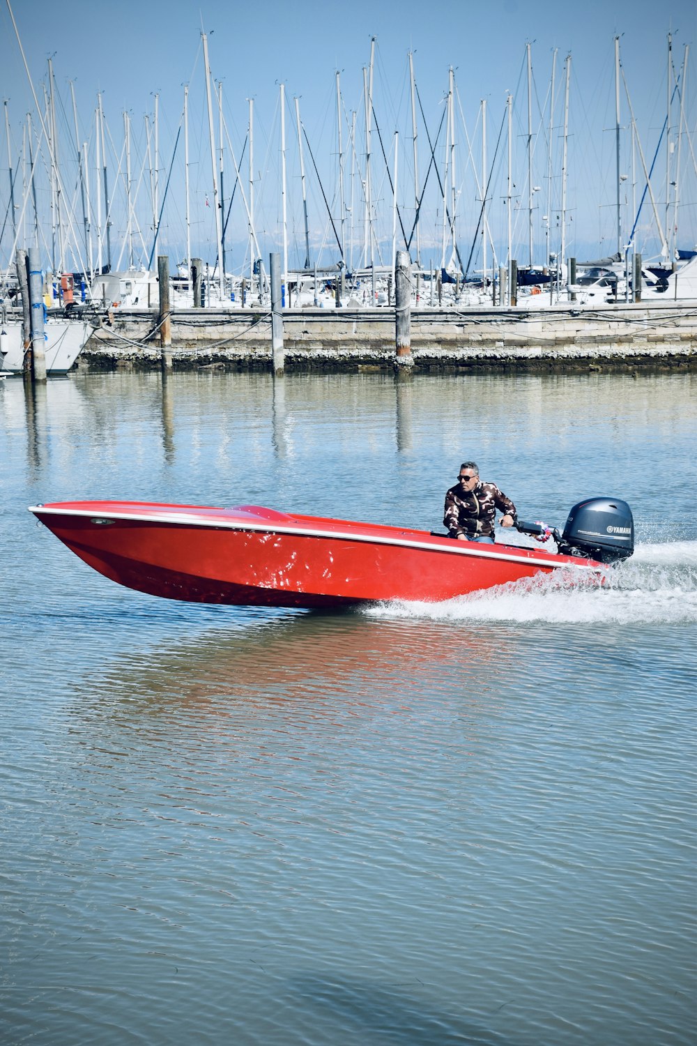 Ein Mann fährt ein rotes Schnellboot auf einem Gewässer