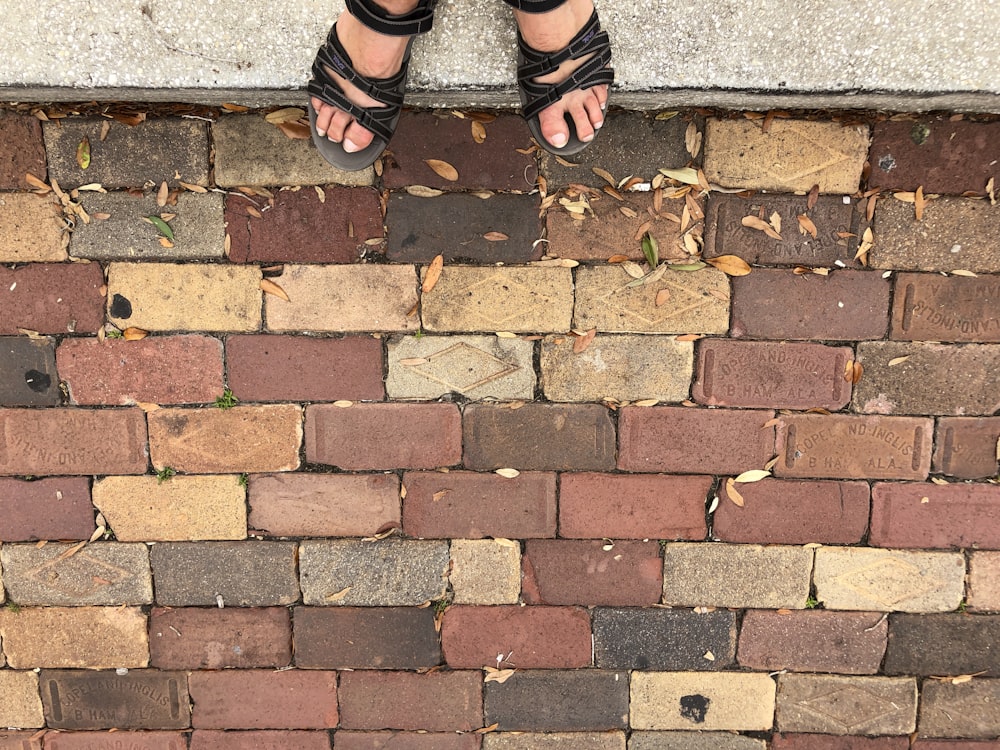 a person standing on a brick walkway with their feet up