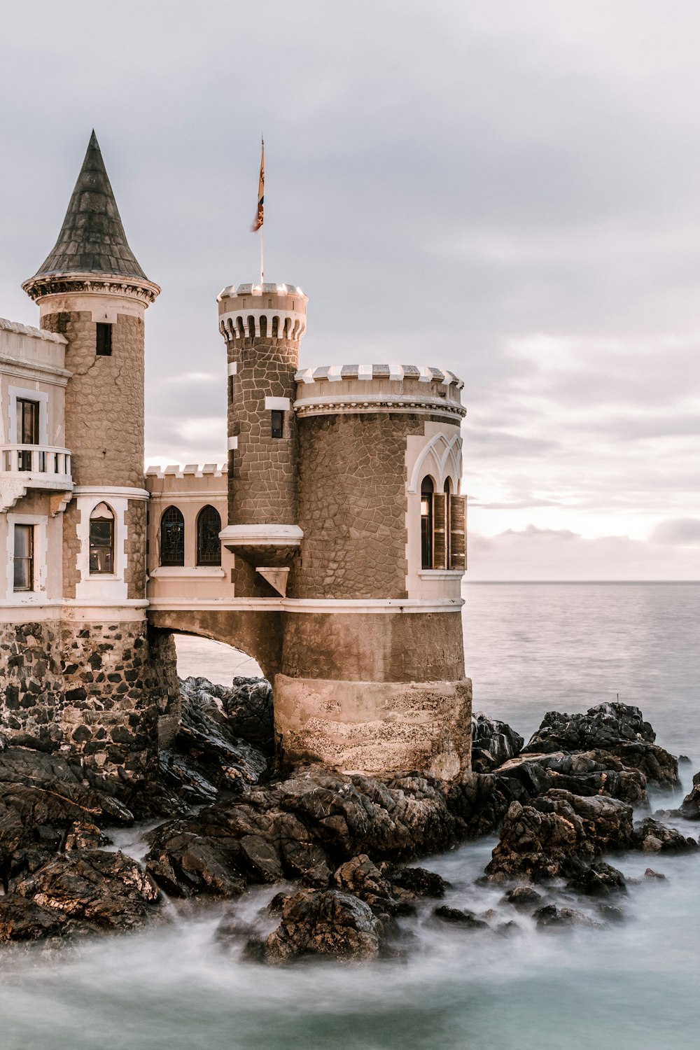 a castle sitting on top of a rock next to the ocean