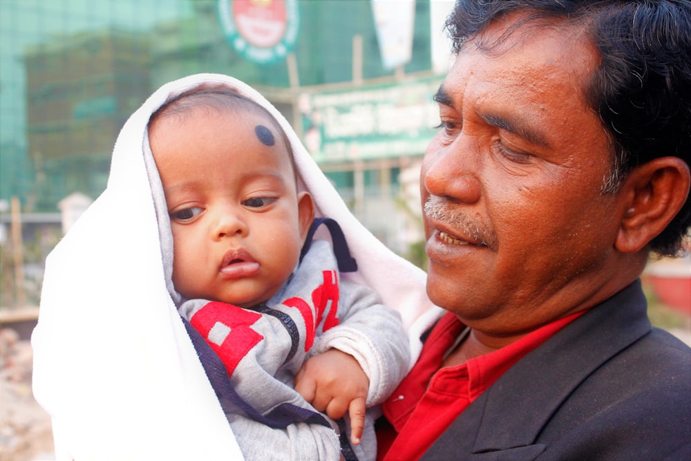 a man holding a baby wrapped in a blanket