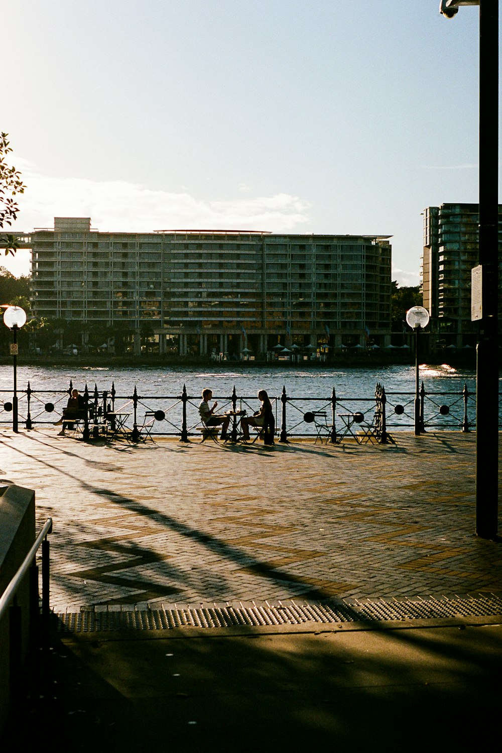 a group of people sitting on a bench next to a body of water