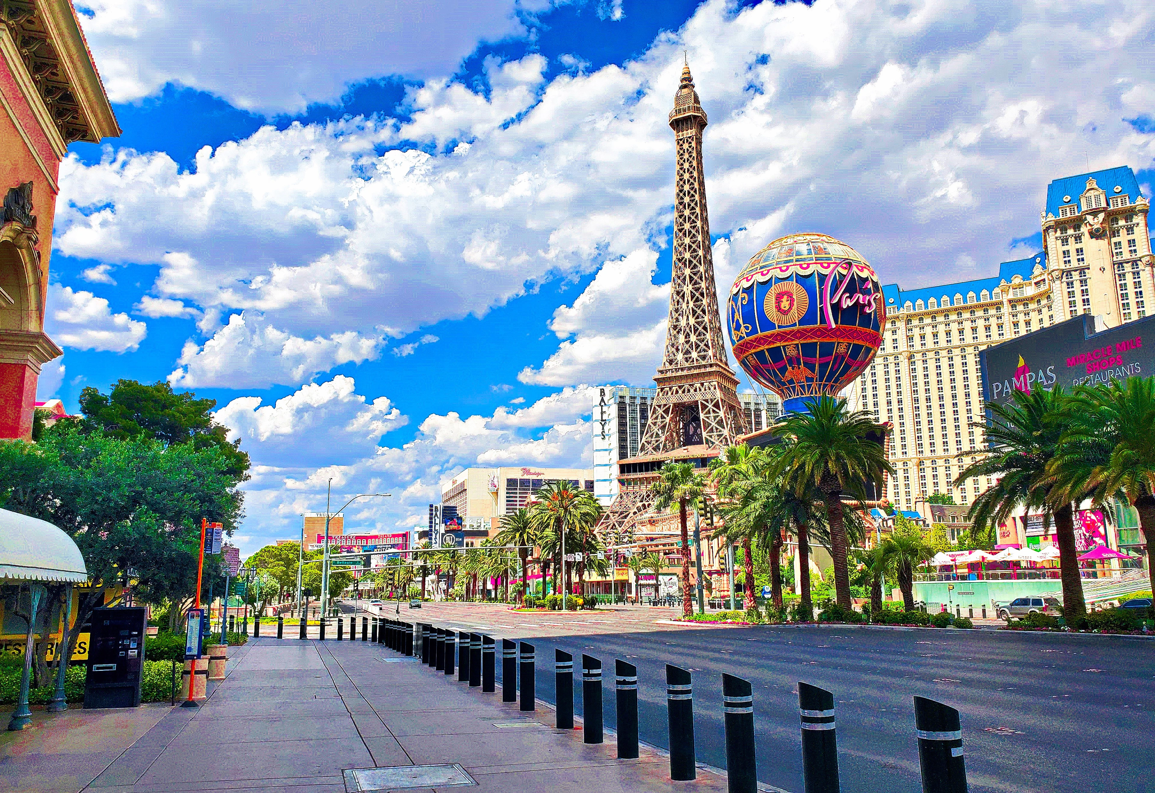 The Eiffel Tower replica and hot air balloon sign at Paris Las Vegas under a bright blue daytime sky.