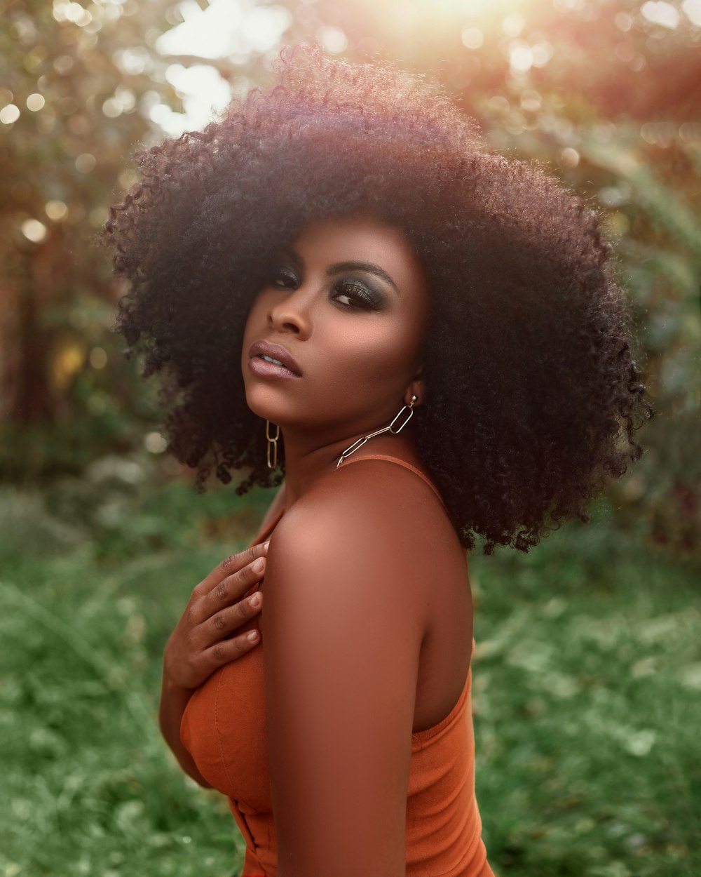 a woman with an afro standing in the grass