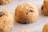 A close-up view of raw cookie dough balls sprinkled with sugar crystals and containing chocolate chips. The texture of the dough is soft, and the chocolate chips are partially visible.
