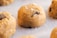 A close-up view of raw cookie dough balls sprinkled with sugar crystals and containing chocolate chips. The texture of the dough is soft, and the chocolate chips are partially visible.