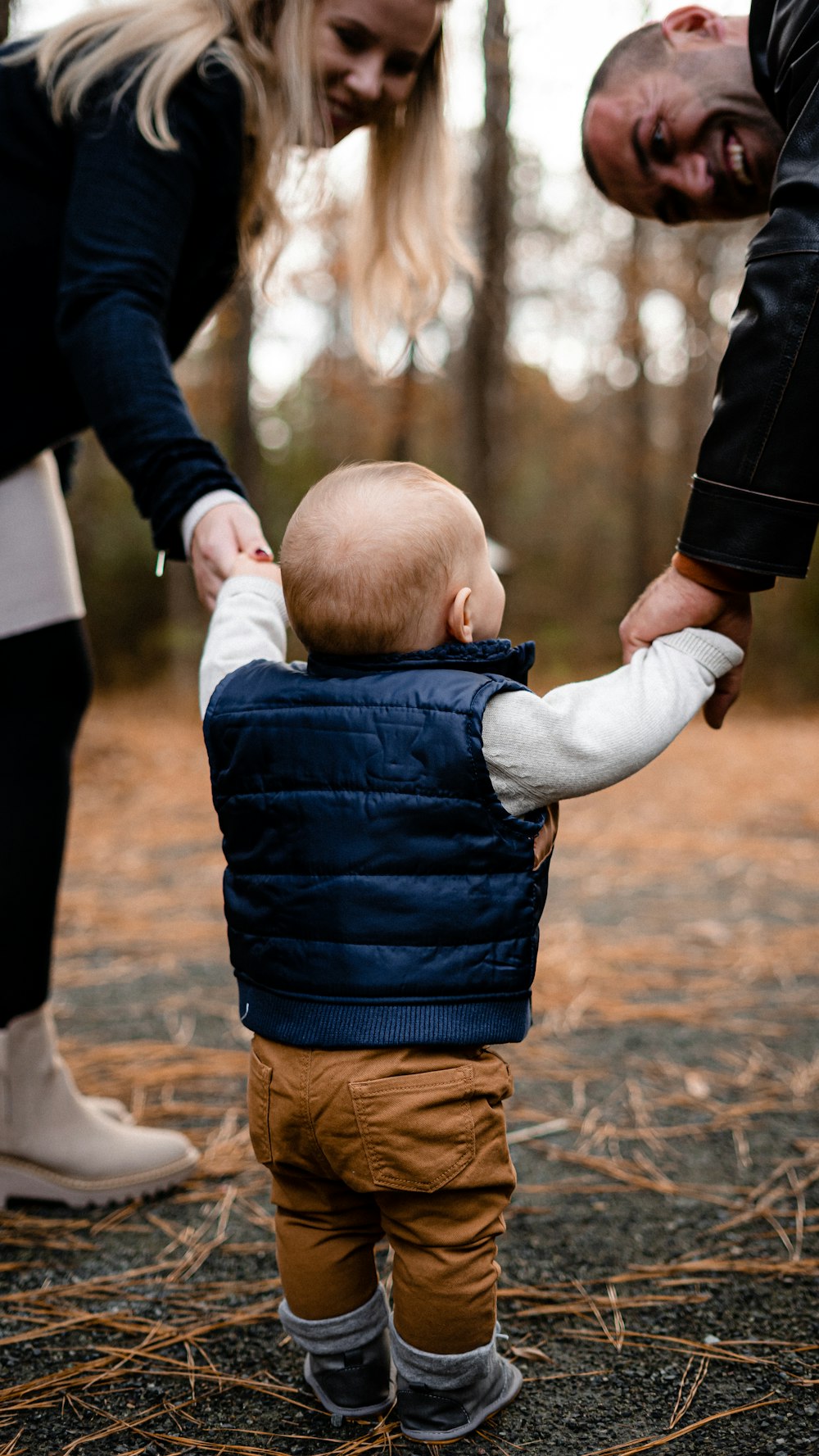 a woman holding a baby's hand while standing next to a man