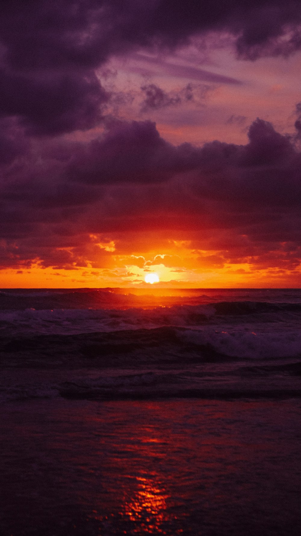 the sun is setting over the ocean on a cloudy day