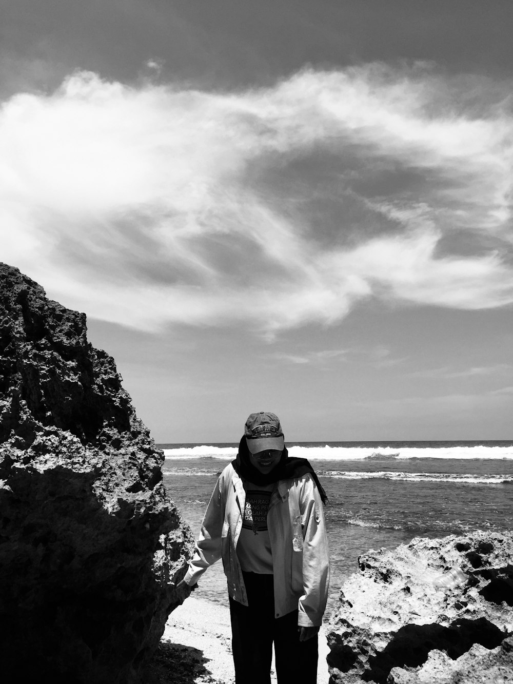 a woman standing on a rocky beach next to the ocean