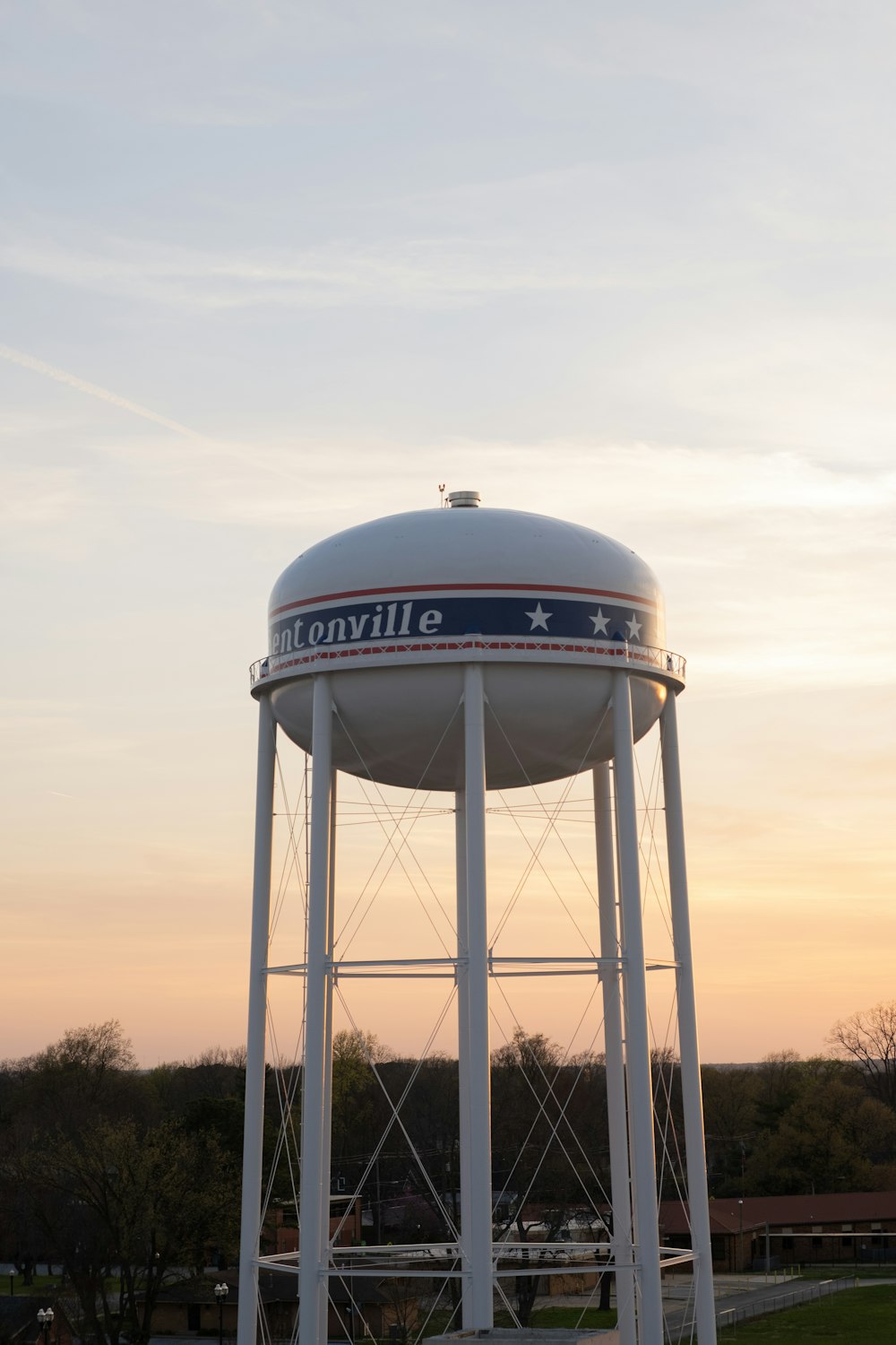 a large white water tower sitting on top of a lush green field